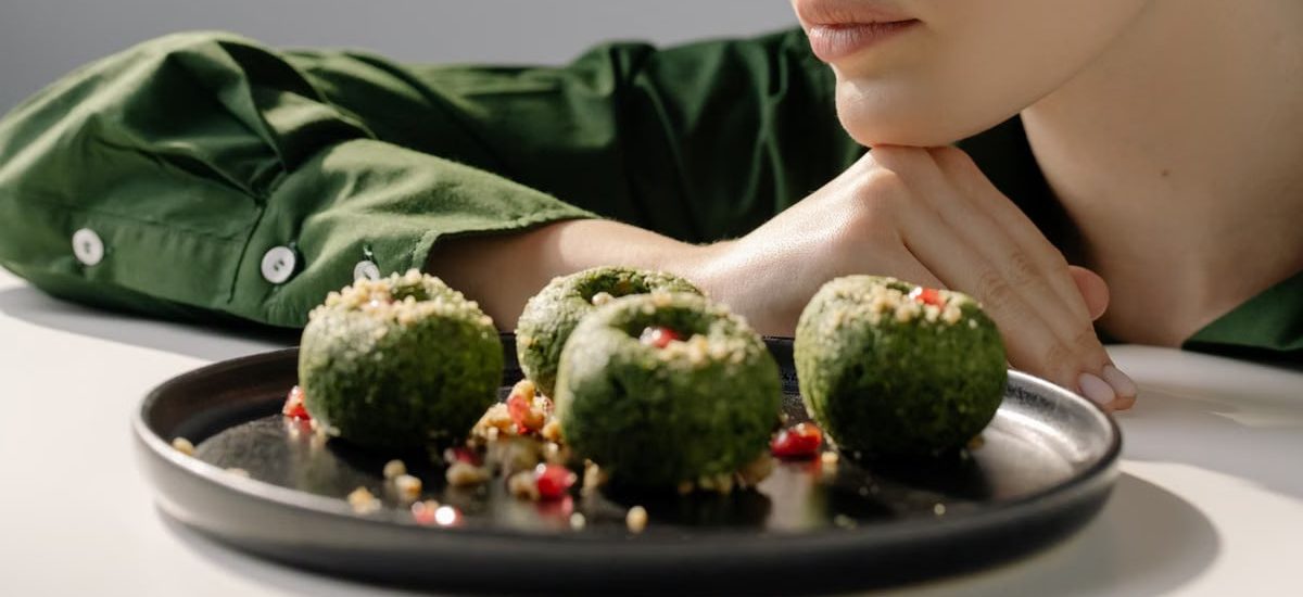 Close-up of spinach pkhali, a Georgian vegan dish, with a woman in green observing.