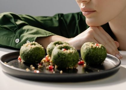 Close-up of spinach pkhali, a Georgian vegan dish, with a woman in green observing.